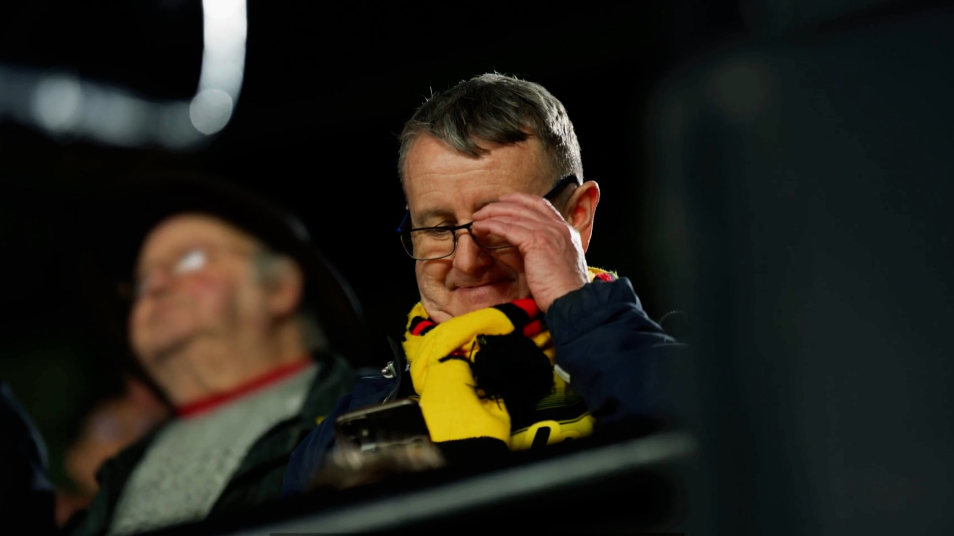 Football fan shares a photo on his smartphone during a football match at Watford FC.