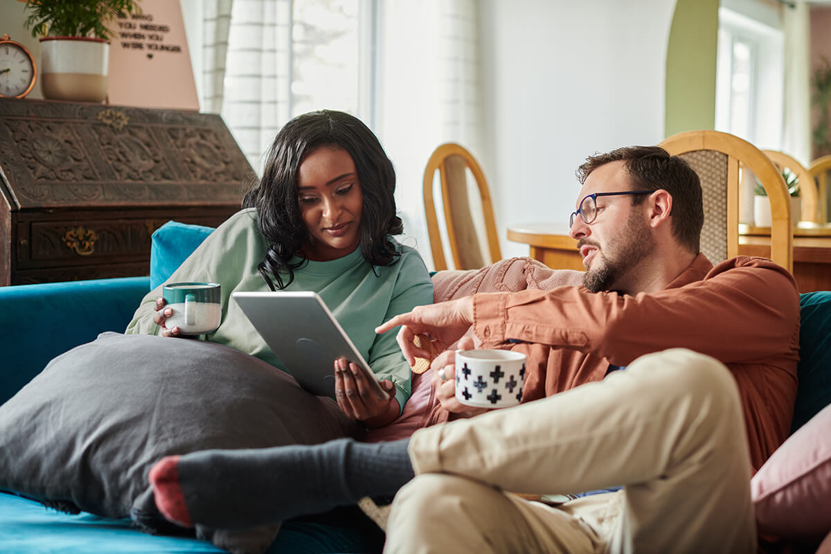 Couple sitting on a sofa looking at a tablet together