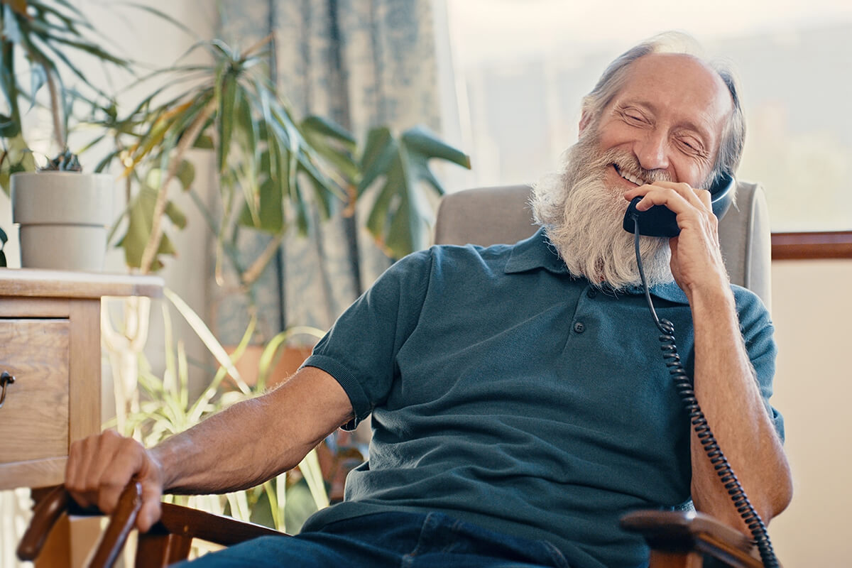 Elderly man using a corded landline telephone