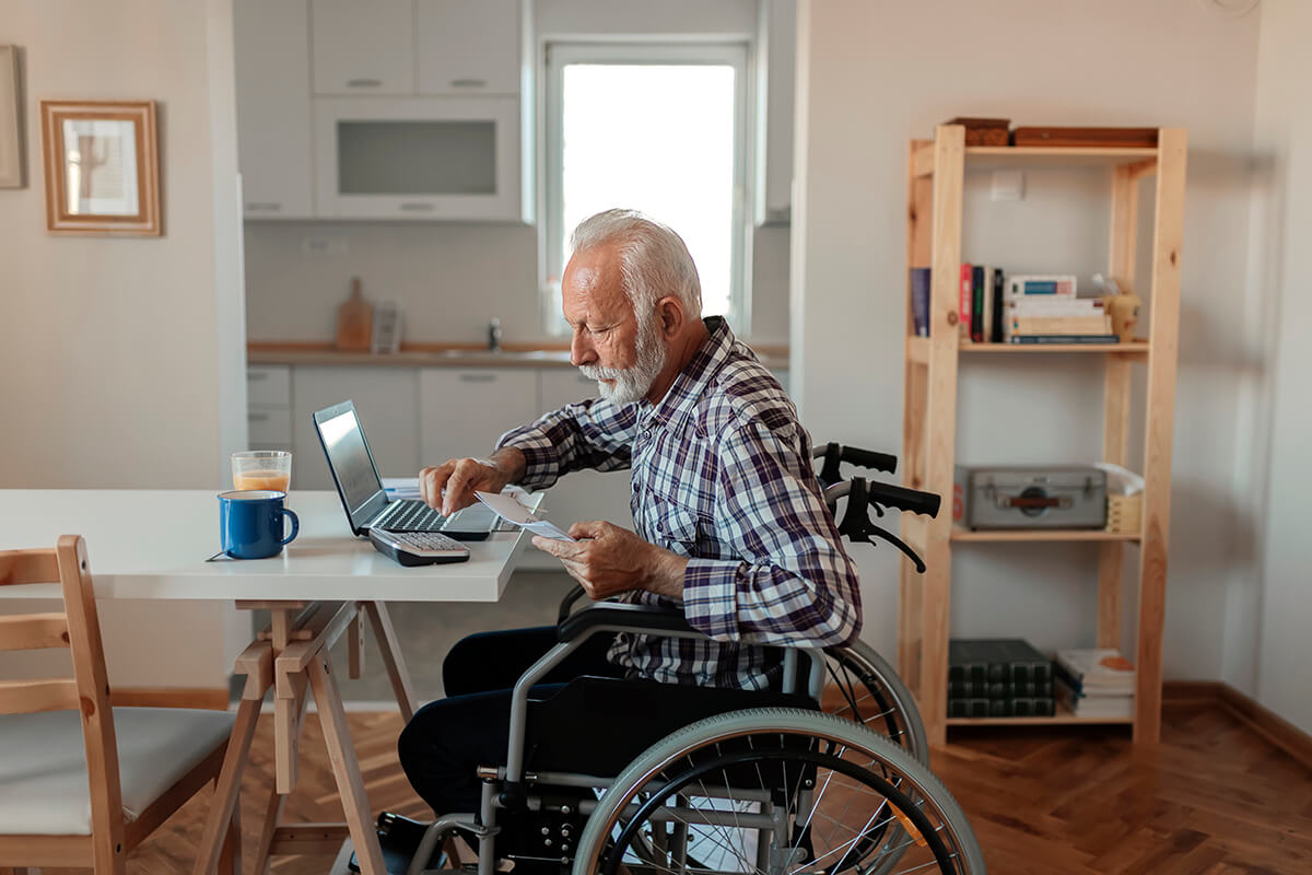 Elderly man in a wheelchair working on a laptop